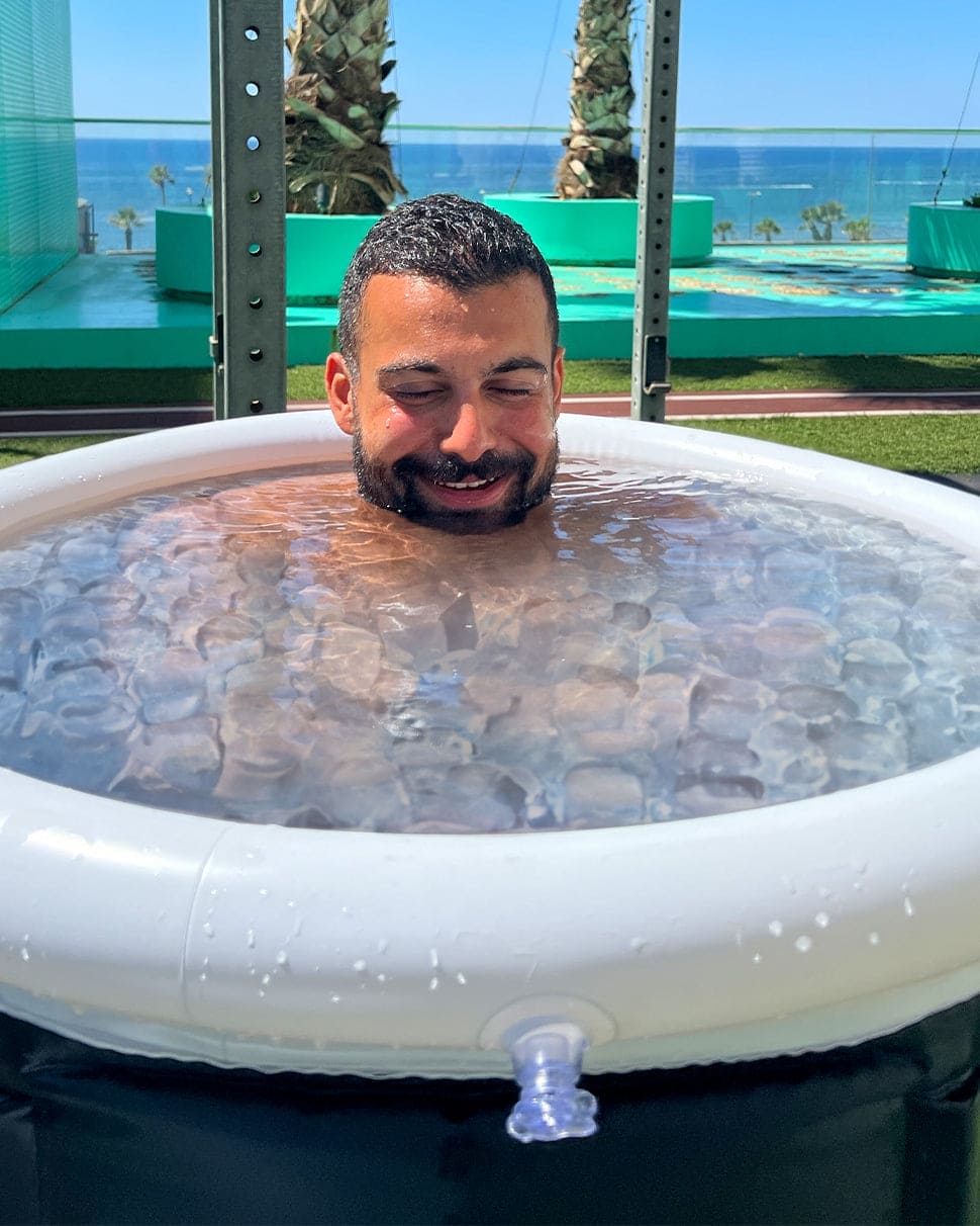 Person experiencing ice plunge therapy in a portable ice tub, promoting muscle recovery and wellness.